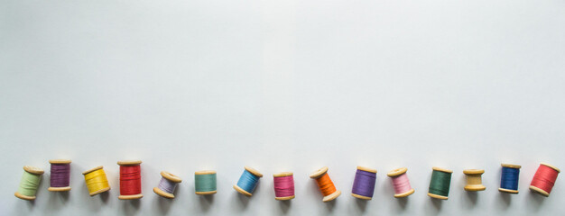 A large banner with lots of multicolored threads on wooden old-fashioned reels on a white...