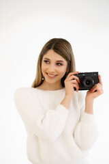 Beautiful Hipster woman taking photos with black retro film camera on white background. Close up. Indoor. Warm color. Blogger