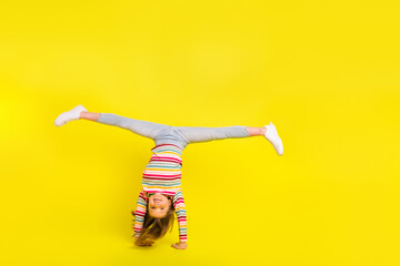 Full body photo of happy young pretty funky girl make handstand good mood isolated on yellow color...