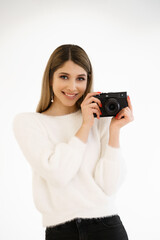 Beautiful Hipster woman taking photos with black retro film camera on white background. Close up. Indoor. Warm color. Blogger