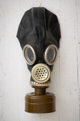 Army gas mask on a white wooden background. Front view of a rubber gas mask.