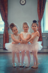 Three funny little ballerinas in tutus are in the ballet class. Image with selective focus and...