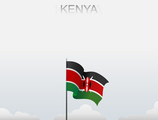 The Kenyan flag flutters on a pole standing tall under a white sky