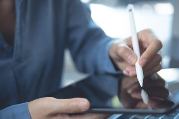 Close up of woman hand using stylus pen signing on digital tablet and working on laptop computer, e-signing, electronic signature concept