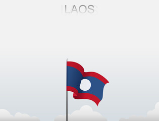 The Lao flag flutters on a pole that stands tall under the white sky