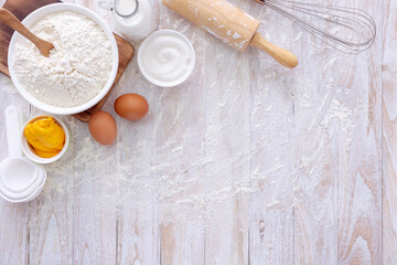 Homemade dough recipe (eggs, flour, milk, sugar) on a wooden table top view.