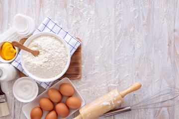 Homemade dough recipe (eggs, flour, milk, sugar) on a wooden table top view.