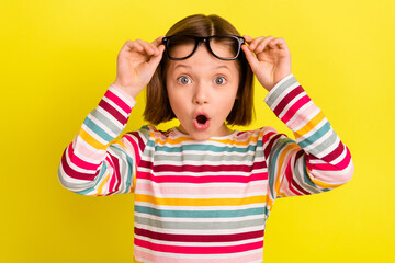 Photo portrait little girl amazed wearing glasses shocked opened mouth isolated vibrant yellow...