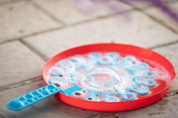 A close-up of a bowl and bubble blower against the backdrop of paving slabs. Selective focus