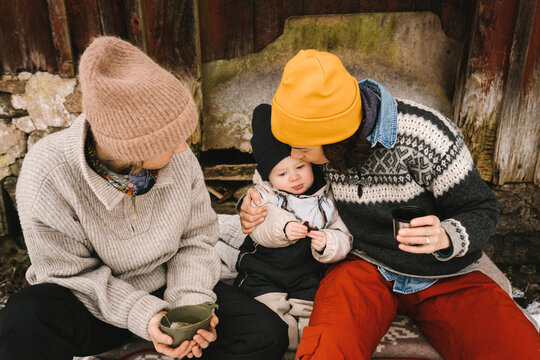 Kvinna tittar p&aring; partner som pussar dotter sittande utomhus