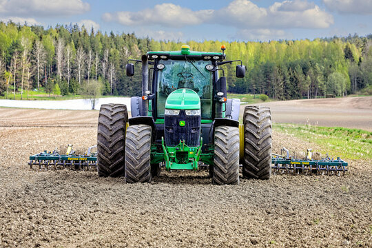John Deere 7230R Tractor and Harrow in Field, Front View. Illustrative Editorial Content. 