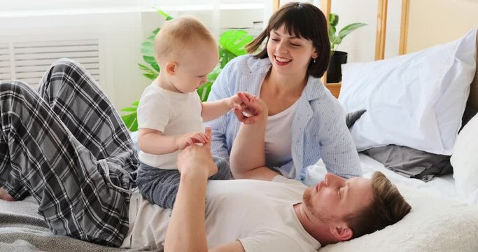 Parents playing with baby son on bed at home