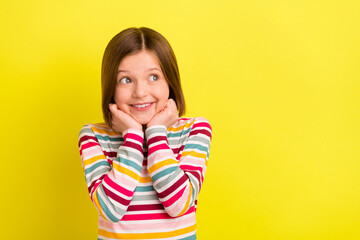 Fototapeta premium Photo of cheerful happy nice small girl look empty space hold hands face isolated on bright yellow color background