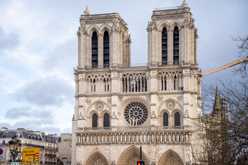 Fototapeta na wymiar Famous facade of Notre-Dame de Paris with tower crane on background