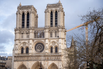 Famous facade of Notre-Dame de Paris with tower crane on background