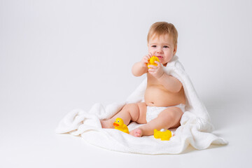 baby boy in a diaper sitting on a white background with a towel and rubber ducks, bathing concept