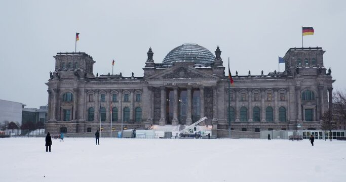 4k video of Berlin Reichstag in the wintertime. People walking through the snow in front of the parliament building