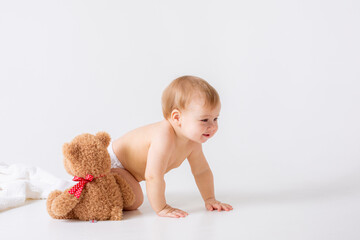 baby boy in a diaper sits on a white background with a teddy bear