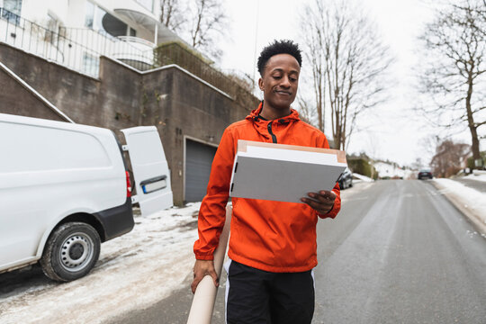Manligt bud l&auml;ser p&aring; paket g&aring;ende p&aring; gatan