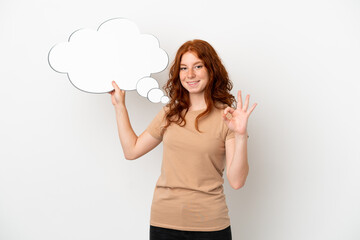 Teenager redhead girl isolated on white background holding a thinking speech bubble and doing OK sign