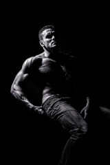 Fototapeta na wymiar Sport workout bodybuilding concept. Handsome big muscles man posing at studio. Leather belt, jeans. Black and white