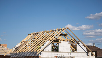 Fototapeta premium Wooden roof construction against blue sky. House building.