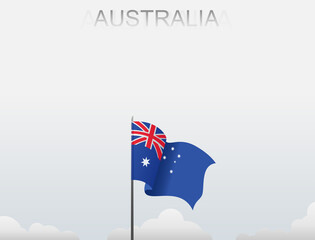 Australian flag flutters on a pole standing tall under a white sky