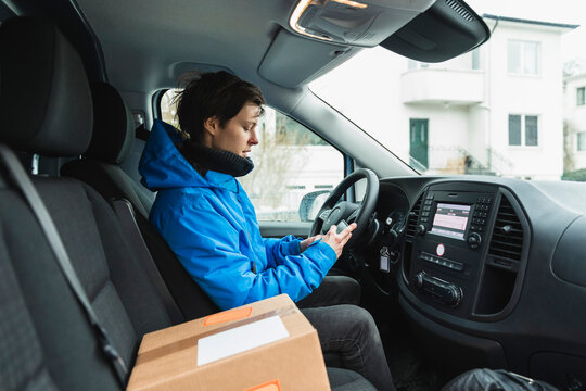 Kvinna sitter i budbil och anv&auml;nder smartphone