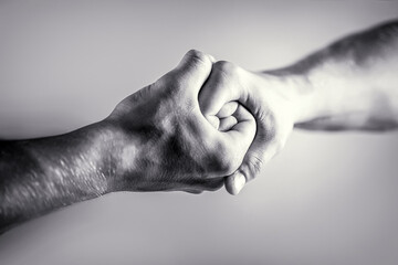Friendly handshake, friends greeting. Rescue, helping hand. Male hand united in handshake. Man help hands, guardianship, protection. Black and white