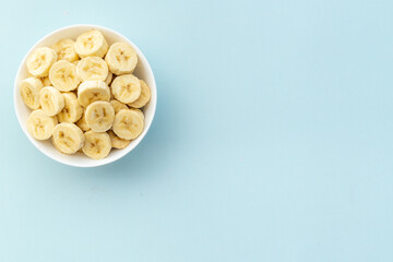 Many banana slices in white bowl. Top view