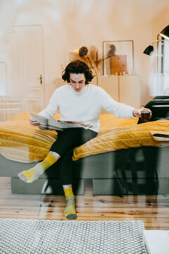 Man sitter i sovrum och l&auml;ser tidning hemma