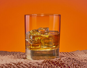 Whisky on the rocks with a cool orange gradient background.