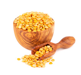 Dry yellow split peas in olive bowl and scoop, isolated on white background. Halves of yellow legume peas.