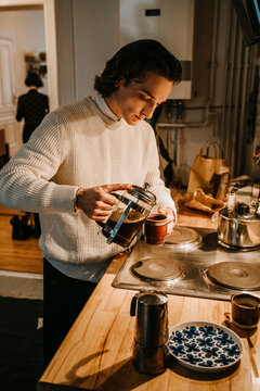 Ung man h&auml;ller upp kaffe i k&ouml;k hemma