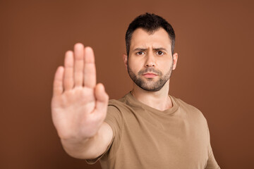 Photo portrait brunet man wearing pastel t-shirt showing stop sign palm isolated brown color...