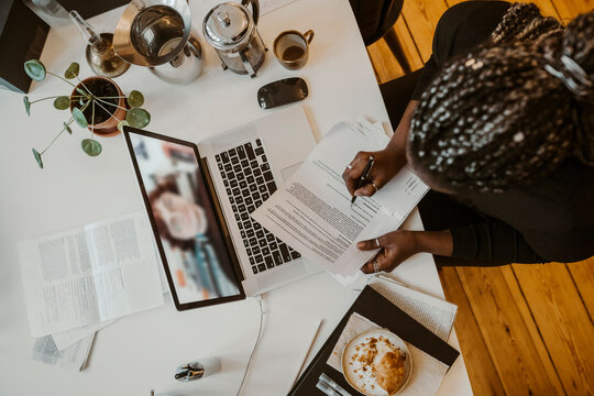 Kvinnlig entrepren&ouml;r sitter vid bord i videom&ouml;te p&aring; laptop hemma