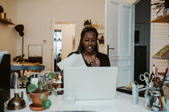 Ung aff&auml;rskvinna sitter i videosamtal p&aring; dator sittande hemma