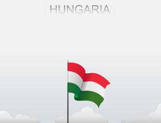 Hungary flag flutters on a pole standing tall under a white sky