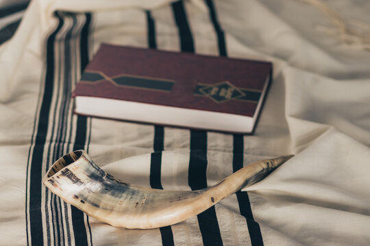 A shofar is placed on a tallit next to a close Torah study book. Before the Jewish holidays on the month of Tishrei