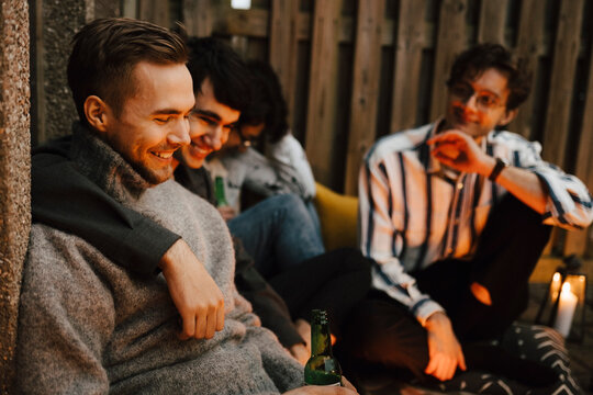 Skrattande man sitter med v&auml;nner och dricker &ouml;l