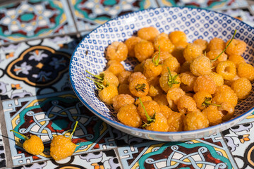 Blue plate full of fresh yellow raspberries on garden table.