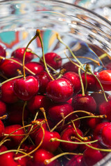 Cherries in water in glass bowl on the  garden table.