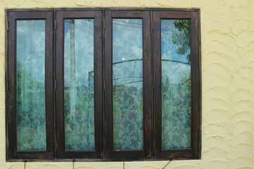 Large wooden window with beautiful curtains and yellow cement walls.