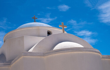 Fototapeta na wymiar White orthodox greek church with cross on clear blue sky background.