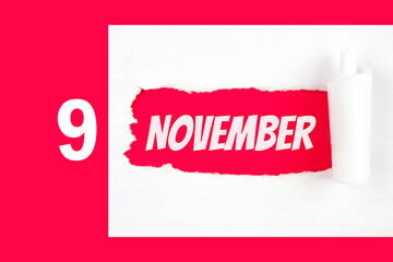 November 9th. Day 9 of month, Calendar date. Red Hole in the white paper with torn sides with...