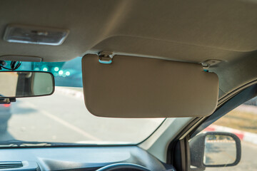 Car visor. Car interior. Grey open sun car visor with selective focus and car mirror on blurred background with automobile window