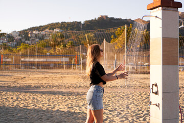 A girl in shorts and a black T-shirt on the beach near the shower. Shower on the beach. Nearby...