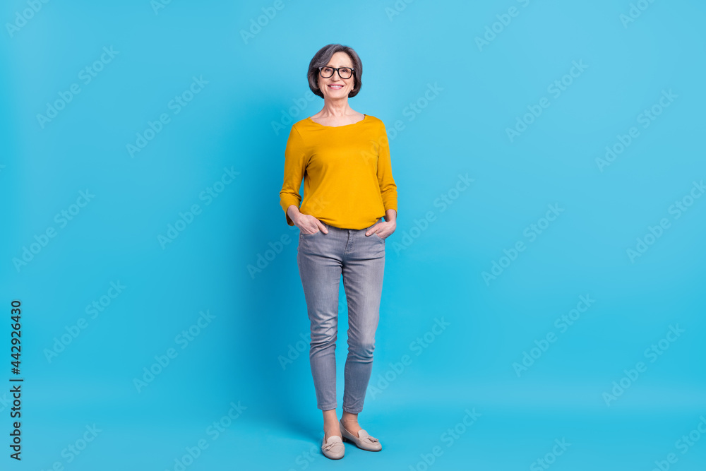 Wall mural full length body size view of attractive cheerful woman holding hands in pocktes isolated over vivid