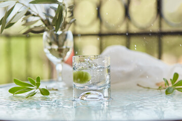 Summer elegant cocktails on the background. Decorative green leaves flowers and a branch of an olive tree in a glass. Glyph of Purification