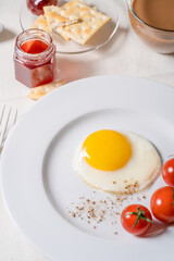 Fried egg with tomatoes on white plate, breakfast dining table